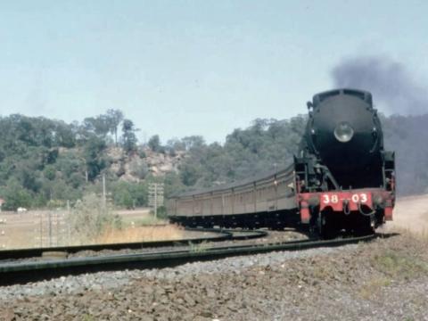 A steam train approaching a curve on a railway track.