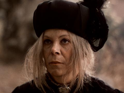 Mrs Appleyard with dishevelled hair under a heavy woollen hat standing in the bush and looking upwards