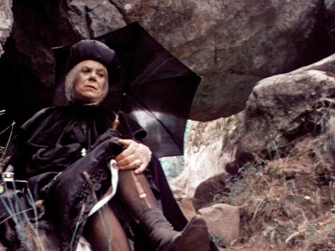 Mrs Appleyard wearing heavy black clothing rests on a rock in an outtake from the film of Picnic at Hanging Rock