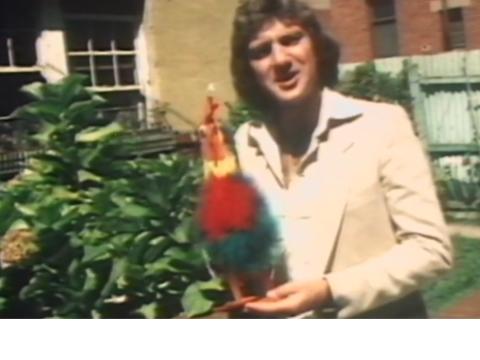 Reporter Greg Evans holds a colourful toy rooster