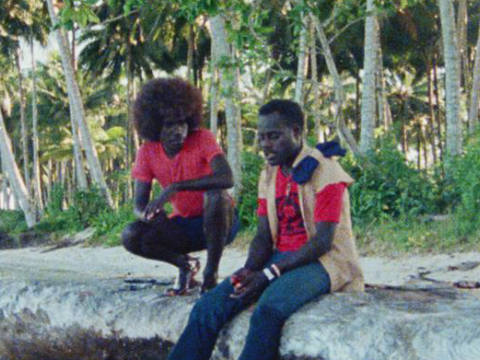 Two men in casual clothes sitting on a rock talking in the highlands of Papua New Guinea.