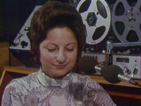 A female radio presenter is looking down at the desk in front of her during 2EA's earliest Greek language broadcast