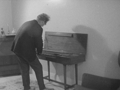 black and white image of composer Ron Granier leaning over an instrument, back to the camera.