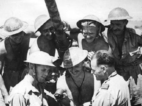 Seven soldiers gathered around a tank