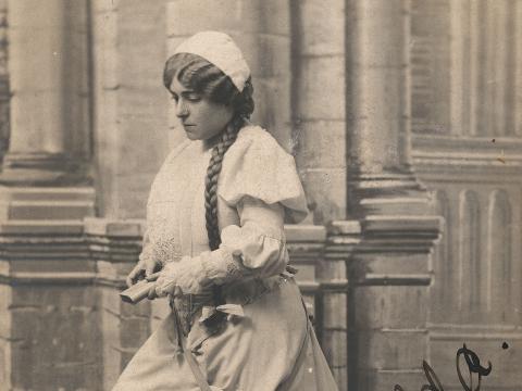 Frances Alda on stage in front of a backdrop of stone columns.
