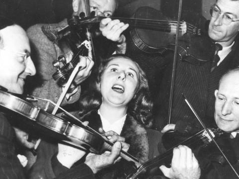 Marjorie Stedeford surrounded by men playing violins