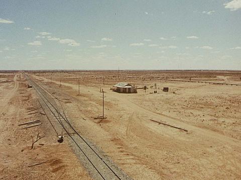 An overhead view of a small outback hotel in the desert. A railway track runs into the distance