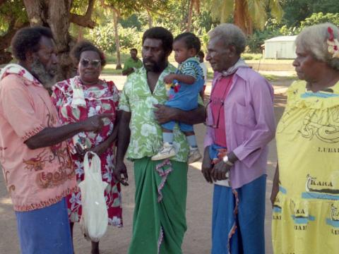 Eddie Mabo talking with four witnesses from Mer (Murray Island). One of the witnesses is carrying a small child.