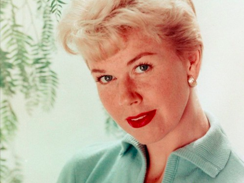 Actress Doris Day pictured circa 1960s wearing a pale blue shirt with a dragonfly brooch. She is looking at the camera with her head tilted slightly to the right.
