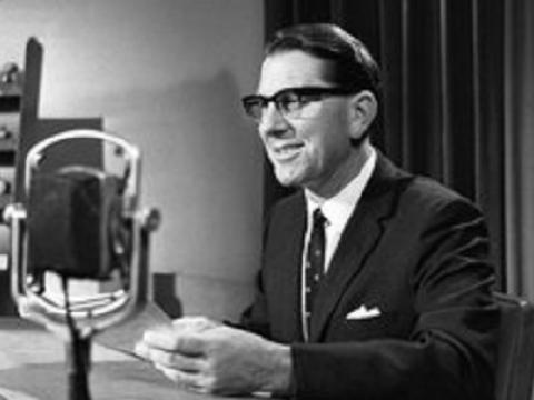 Newsreader Martin Royal in suit and tie at the microphone.