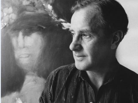 Artist Sidney Nolan is looking reflective. He is posing next to one of his artworks.