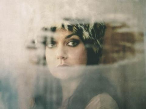 Portrait of Leah Flanagan shot through a hole torn in fabric screen.