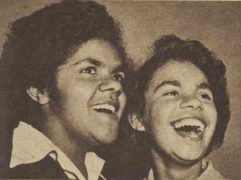 Sepia photo of two young Indigenous women singing.