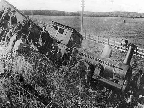 Black and white image of a train derailment in Warrnambool, c1897, showing train at the bottom of an embankment surrounded by onlookers.
