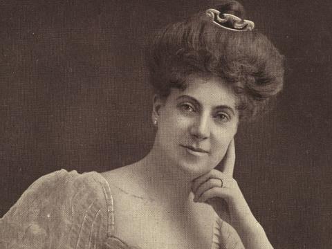 Head and shoulders portrait of Ada Crossley with the hair in a bun and face resting on her hand.