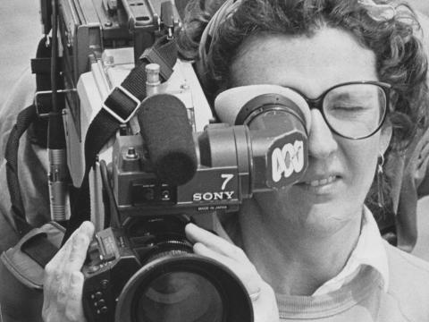A woman is operating a news camera.