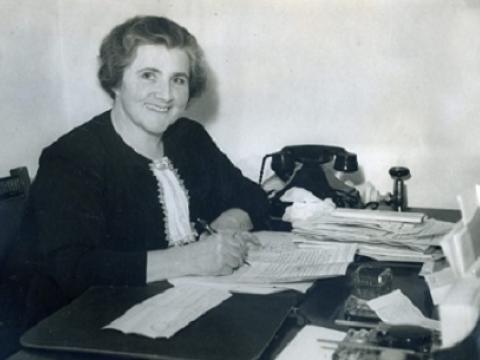 Dame Enid Lyons at her desk, writing.
