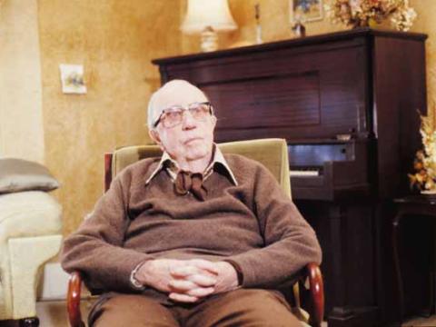 Singer Jack O'Hagan is sitting in an armchair in a home with a piano in the background.
