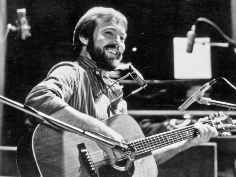 Australian singer/songwriter John Williamson holding a guitar and standing in front of a microphone