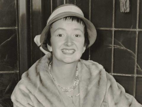 A young woman is wearing a fur coat and hat posing for the camera.