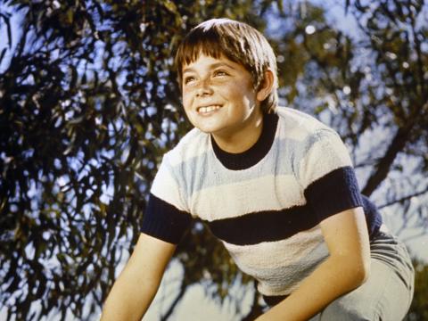 Garry Pankhurst as Sonny Hammond leaning forward on a rock in the bush.
