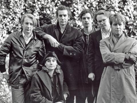 A band (group of six people) standing in a garden posing for camera