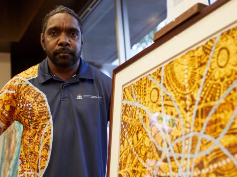 A man posing next to a framed colourful artwork