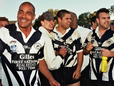 A group of football players in black and white uniform shaking hands and smiling
