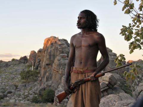 A young man holding a rifle in the Australian outback.