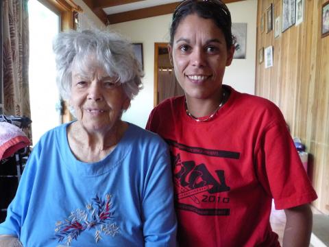 A young and elder woman standing next to each other pose to camera