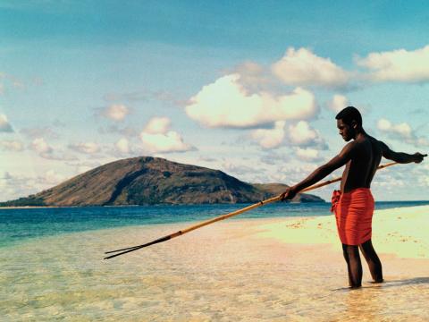 A Torres Strait Islander man spearfishing on a beach