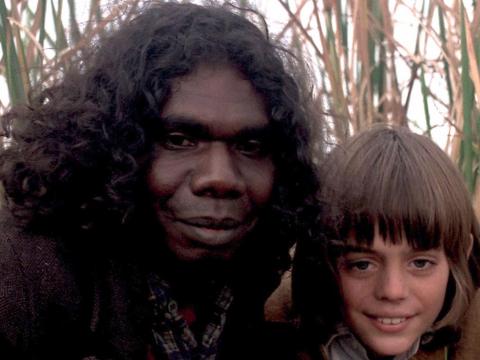 David Gulpilil as Fingerbone Bill and Greg Rowe as Storm Boy next to each other in the long grass