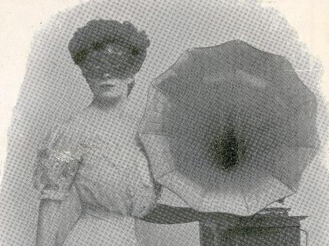 A masked woman stands next a gramophone.