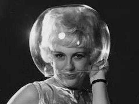 A woman wearing a fishbowl on her head as a helmet