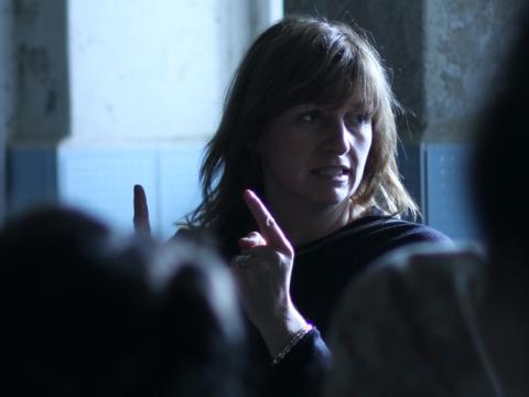 Director Cate Shortland directs a room full of people. We see the other people from behind and out of focus.
