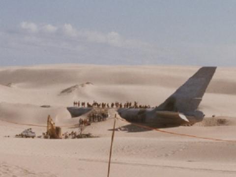 Crashed airplane partially covered with sand.