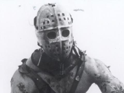 Muscular man wearing an ice hockey mask.