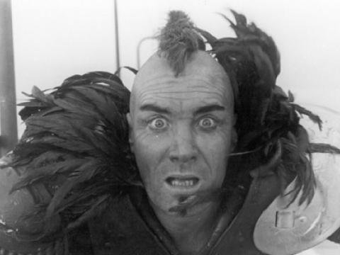 Crazed looking man with a mohawk haircut.