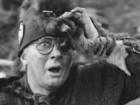 Startled looking man wearing a strange animal pelt hat.