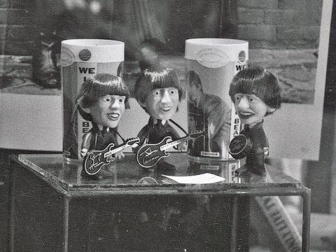 A window display at a record store in 1964 promoting The Beatles. The display features memorabilia including Beatles dolls and cups. 