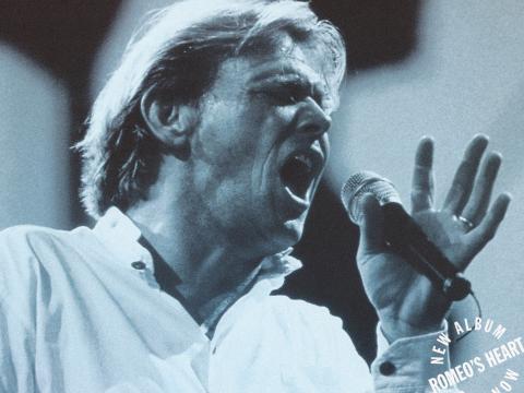 Close up of John Farnham holding a microphone and singing, circa 1996.