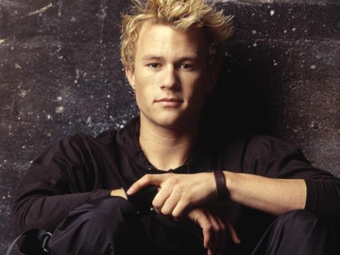 A close-up of actor Heath Ledger. He is dressed in black and looking directly at the camera.