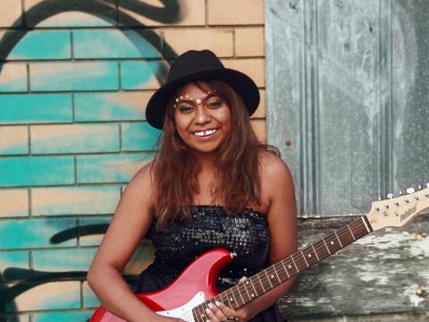 Portrait of Emily Wurramara holding an electric guitar.