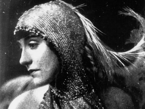 A black and white head shot of Annette Kellerman, wearing a sequinned costume with feathers as part of the head-dress.
