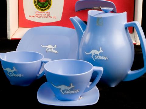 Blue plastic tea set with kangaroo motif in red cardboard box. 'Skippy Tea Set' logo on box