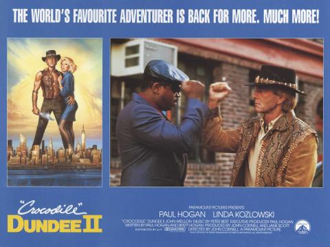 A lobby card for Crocodile Dundee II. There is a picture on of Paul Hogan (Mick Dundee) and Linda Kozlowski (Sue Charlton), a picture of Mick fistpumping with Reginald VelJohnson (Gus the driver), and production company, cast and crew information.