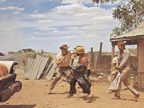 Jack Thompson play fights with Donald Pleasence in the dust, in a still from the 1971 film Wake in Fright
