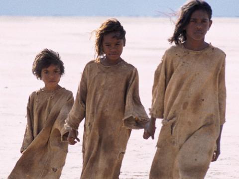 Tianna Sansbury as Daisy, Laura Monaghan as Gracie and Everlyn Sampi as Molly walking hand in hand across a salt flat.