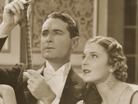 Publicity still of Lloyd Hughes as Daubenny Carshott and Elaine Hamill as Stella Raff examining a film strip.