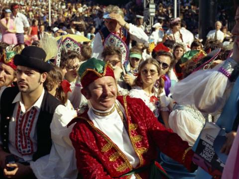 A crowd of people gather for the opening of the Sydney Opera House. Some of them are dressed in national dress of different countries.